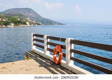 Lifebuoy on the parapet against the background of the sea. In the background, in blur, Mount Castel. View from the village Utyos(Utes)
