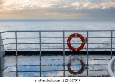 Lifebuoy reflecting in a wet ferry deck at sunset