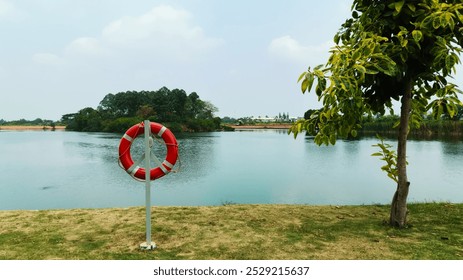 Lifebuoy with a rope attached to a pole on the shore of the lake. Life buoys serve as an important safety tool for lake visitors. - Powered by Shutterstock