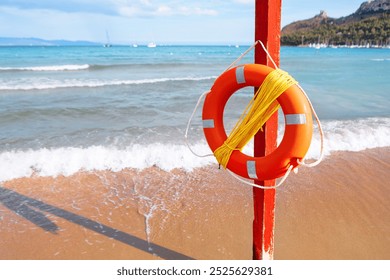 Lifebuoy with rope mounted on a pole on the beach. Life preserver serving as a vital safety measure for beachgoers - Powered by Shutterstock