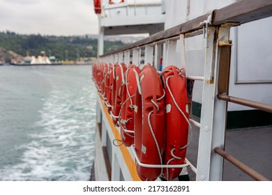Lifebuoys hang on board a sea ferry floating on the waves. Orange life buoys on the ship.