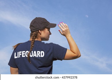 A lifeguard girl with braids and fuscia nail polish is on duty under an azure sky with a daytime moon.