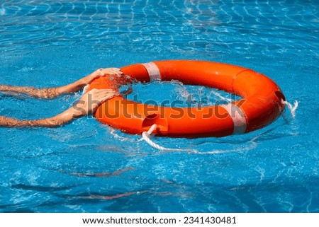 Lifeguard girl training with a life preserver swimming in the pool.
