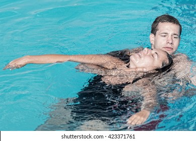 Lifeguard Rescue Training - Young Man Swimming With Drowning Victim, Keeping Her Head Above Water Surface