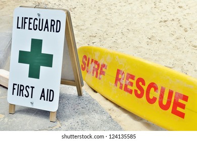 Lifeguard sign first aid and surf rescue surfboard on sandy beach - Powered by Shutterstock