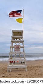 Lifeguard Stand On A Cloudy Day At Indian Wells Beach, Amagansett, The Hamptons, NY, With American Flag Blowing In The Wind