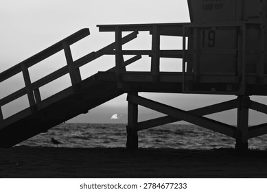 Lifeguard Tower 19 frames the setting sun over the ocean in Hermosa Beach, California.