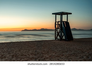 Lifeguard tower on empty beach at sunset