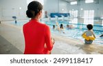 Lifeguard, woman and supervision at swimming pool with duty for children safety, monitoring and protection. Recreation, person and back with watching kids in water for helping, lifesaver and rescue