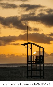 A lifeguard's booth, inside which the setting sun can be seen against the background of the sea.