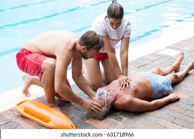 Lifeguards pressing chest of unconscious senior man at poolside - Powered by Shutterstock