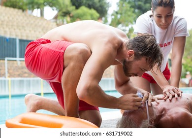 Lifeguards pressing chest of unconscious senior man at poolside - Powered by Shutterstock