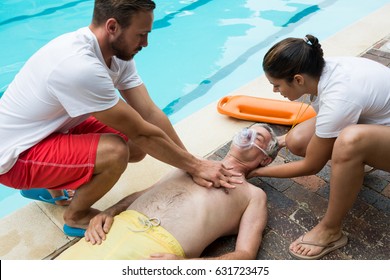 Lifeguards pressing chest of unconscious senior man at poolside - Powered by Shutterstock