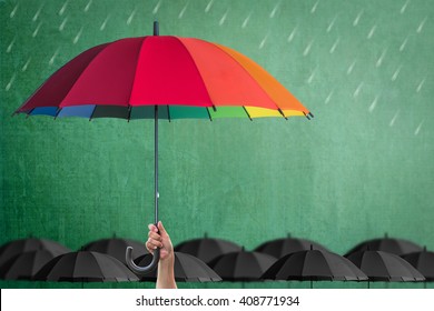 Life-health Insurance Protection Or Business Financial Leadership Concept With Leader's Hand Holding Rainbow Umbrella On Green Chalkboard 