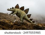 Life-size reproduction of a stegosaurus dinosaur walking in the fog.