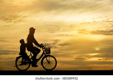 Lifestyle Of Asia Family Ride The Bicycle For Good Healthy. Silhouette Of Mother And Son, Cycling Together. Background Image Is Sunset And Beautiful Sky In Thailand. Happy Family Concept.