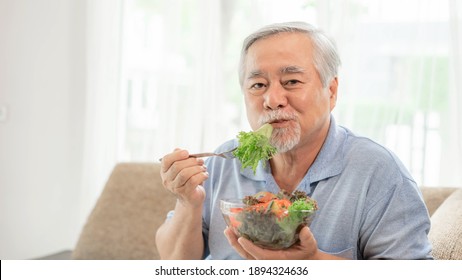 Lifestyle Asian Senior Man ,old Man Feel Happy Enjoy Eating Diet Food Fresh Salad On Sofa