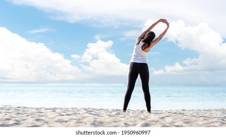Lifestyle athletic woman warm up and raise arm before yoga exercise for healthy life. Young girl or people pose balance body vital zen and meditation workout and fitness sport outdoor on sand beach.