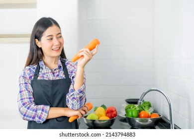 Lifestyle beautiful Asian healthy girl fill Happy , carrot in hand , Washing vegetables in the kitchen sink - Powered by Shutterstock