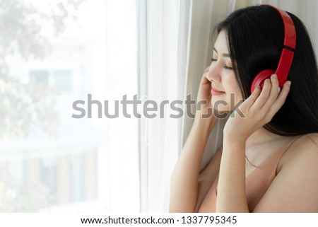 Lifestyle Beautiful asian woman cute girl  feel happy enjoy listening to music with earphones headphones on white bedroom