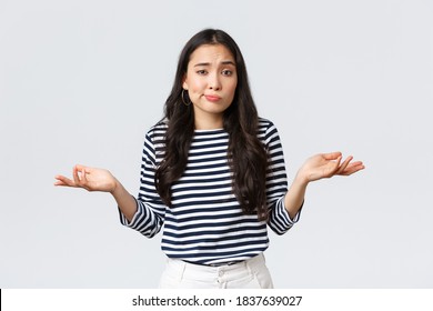 Lifestyle, Beauty And Fashion, People Emotions Concept. Smiling Cute Clueless Girl Dont Have Idea, No Answer, Shrugging With Hands Spread Sideways, Standing White Background