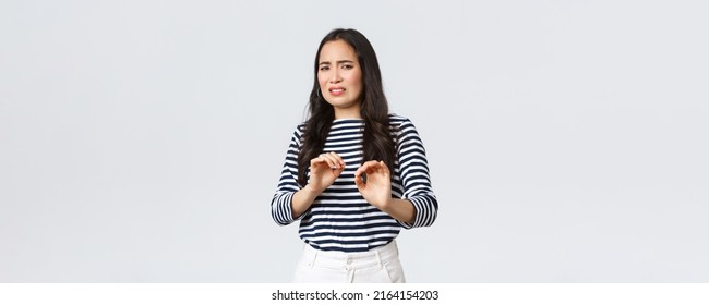 Lifestyle, beauty and fashion, people emotions concept. Reluctant and disgusted asian woman tell to stay away from her, step back and raising hands up defensive, grimacing from aversion and dislike