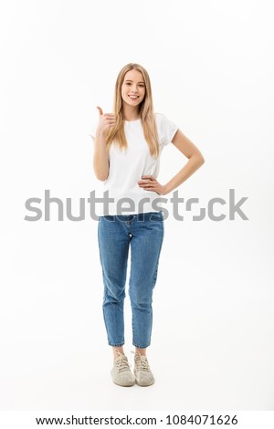 Lifestyle Concept: Happy smiling young woman in jeans looking at the camera giving a thumbs up of success and approval isolated on white
