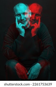 Lifestyle concept. Studio portrait of happy man with sweatshirt looking at camera with smile and holding one hand on cheek. Red and blue color split effect style. 3D glitch virtual reality effect