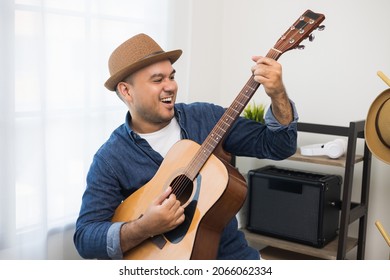 Lifestyle concept. Young asian musician playing guitar in living room at home on this weekend. Relaxing with song and music. Asian man having fun playing acoustic guitar - Shutterstock ID 2066062334