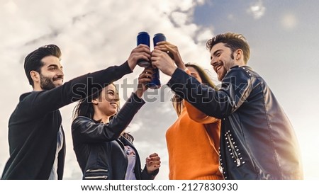 Lifestyle concept of young people raising hands with canned beers and having fun celebrating toasting together