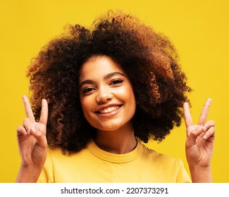 lifestyle, emotion and people concept: Photo of adorable shiny african woman wear yellow t-shirt showing v-sign smiling isolated yellow color background - Shutterstock ID 2207373291