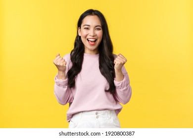 Lifestyle, emotions and advertisement concept. Cheerful and excited cute asian girl winning lottery, feel luck and upbeat, triumphing over achievement, say yes and fist pump rejoicing