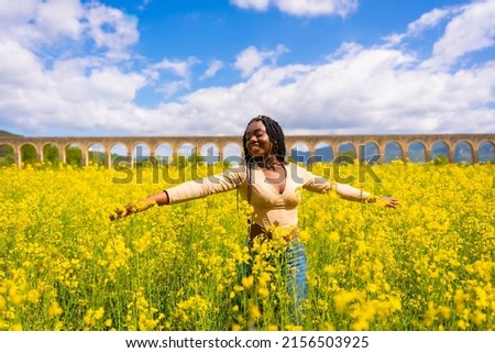 Lifestyle, enjoying nature in freedom, portrait of a black ethnic girl with braids, in a field of yellow flowers