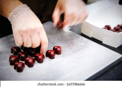 Lifestyle food photography of a caucasian male chocolate factory worker, a chocolatier packing wholesale boxes with finished chocolate ganache hearts