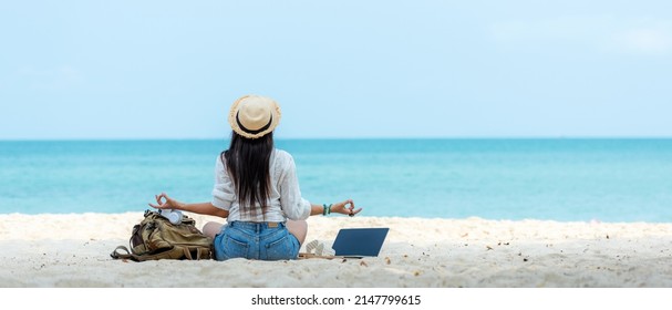 Lifestyle freelance woman relax and sitting meditation on the beach.  Asian people using laptop working for success and together your work pastime and meeting conference on internet in holiday