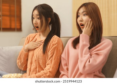 Lifestyle at home concept, LGBT lesbian couple watching horror movie with excited and shock face. - Powered by Shutterstock