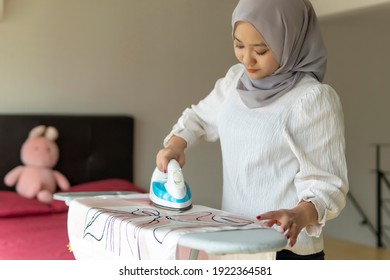 Lifestyle at home, cute malay woman doing routine housework by ironing clothes
