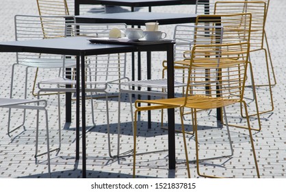 Café Lifestyle Image Of Gold, Silver And Black Outdoor Café Tables And Chairs In The Bright Sunshine