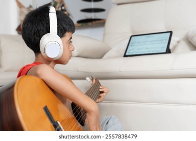 Lifestyle: Latino boy reads sheet music on tablet and learns new songs on his acoustic guitar - Powered by Shutterstock