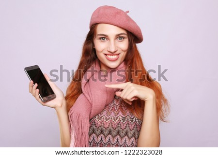 lifestyle  and people concept: Smiling woman is pointing on smartphone, studio shoot