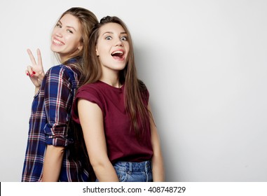 lifestyle and people concept: Two young girl friends standing together and having fun. Looking at camera.