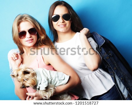 lifestyle and people concept: Two young girls friends standing together and holding dog