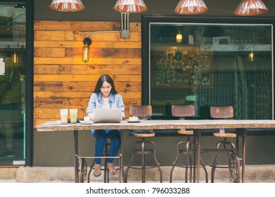Lifestyle people concept, young hipster asian woman enjoying online social connection through laptop computer at coffee retail shop on weekend, urban