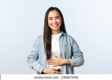 Lifestyle, People Emotions And Beauty Concept. Pleased Smiling Asian Woman Rubbing Her Belly, Being Full After Eating, Pleased Feeling In Stomach From Drinking Yoghurt