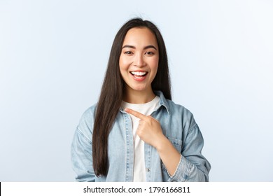 Lifestyle, people emotions and beauty concept. Happy laughing asian girl found something funny, showing way, pointing finger left, telling about big promo, special discounts at store