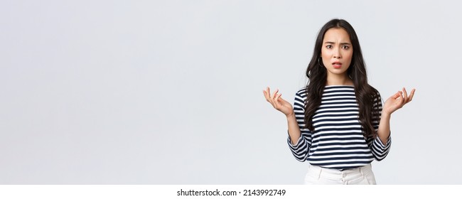 Lifestyle, people emotions and casual concept. Confused disappointed asian woman raise hands up in dismay and frowning upset as learn shocking bad news, cant understand what happened