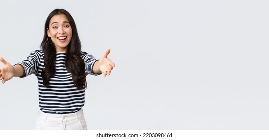 Lifestyle, People Emotions And Casual Concept. Friendly Charming Asian Girl Reaching Hands Forward To Hold Something, Giving Hug Or Embracing, Standing White Background