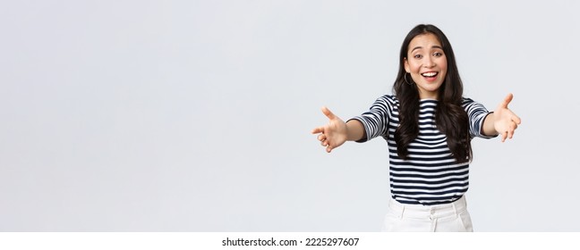 Lifestyle, People Emotions And Casual Concept. Friendly Charming Asian Girl Reaching Hands Forward To Hold Something, Giving Hug Or Embracing, Standing White Background.