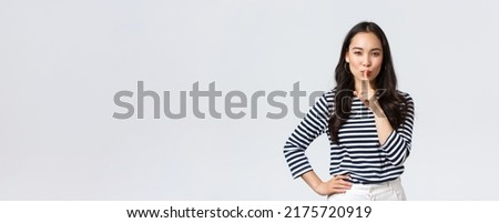 Lifestyle, people emotions and casual concept. Smiling cute asian girl asking keep secret, take promise not tell or be quiet about it, show shush sign, hush with finger over mouth, prepare surprise