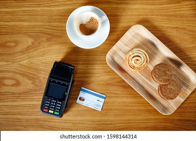 Lifestyle Photograph Of EFT Credit Card/debit Card Machine Sitting On A Shop Counter Photographed Overhead With Credit Card, Espresso Coffee And Tray Of Pastries